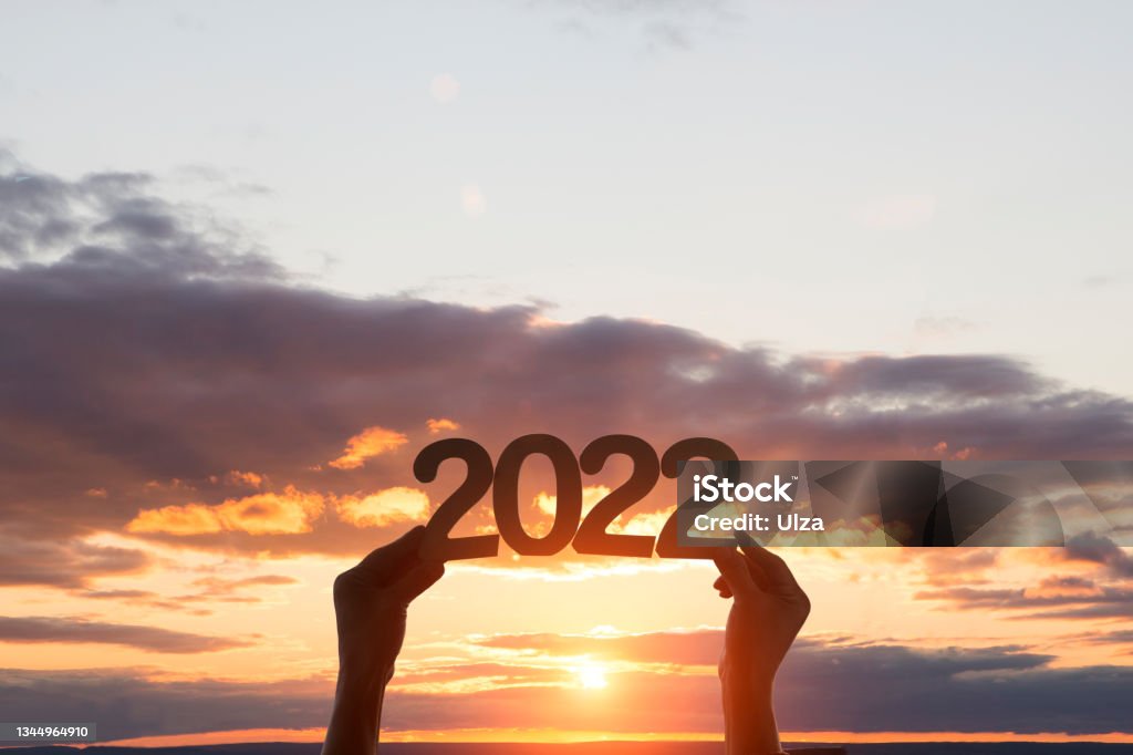 hands hold wooden numbers 2022 against the background of sunset sky. ecology.  Happy New Year concept. copy space. merry Christmas 2022 Stock Photo