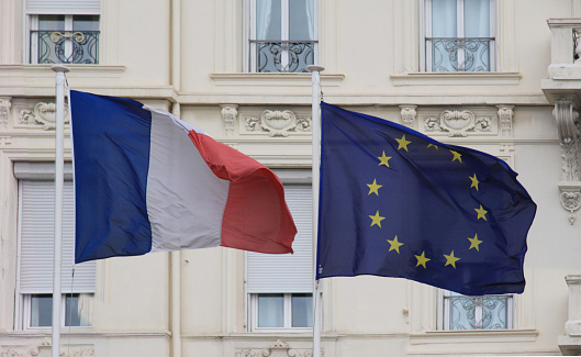 European Union EU and french flag - Tricolore - for France on  poles waving in the wind with a classic palace in background