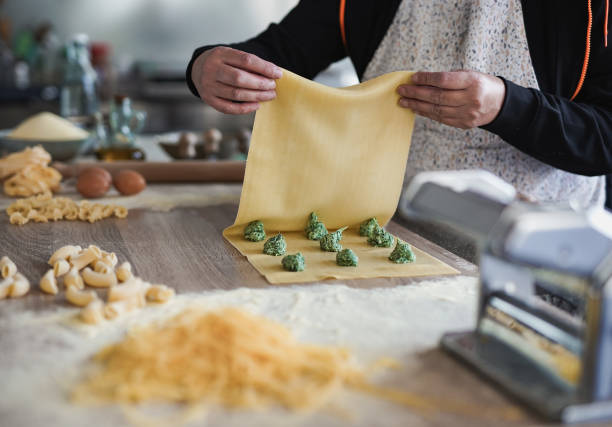Mature woman preparing fresh made ravioli with ricotta cheese and spinach inside pasta factory Mature woman preparing fresh made ravioli with ricotta cheese and spinach inside pasta factory italian ethnicity stock pictures, royalty-free photos & images