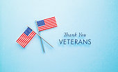 Veteran's Day Message Sitting Next to Tiny American Flag Pair  on Blue Background