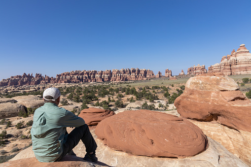 Hiker resting on an overlook in the Needles District of Canyonlands National Park, Utah, USA