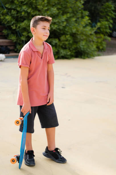 istock A boy is standing outside holding a skateboard and he is tired 1344969692