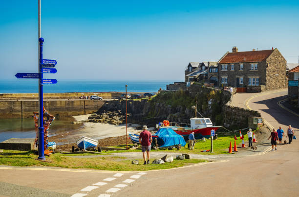 Craster village, Northumberland, England Craster, England - September, 08 2021: Day trippers and tourists walking eastwards along Haven Hill in the Northumberland village of Craster. craster stock pictures, royalty-free photos & images