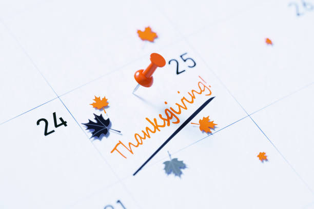 Thanksgiving Concept - Thanksgiving Note Pinned By An Orange Thumbtack On A White Calendar Thanksgiving note over white calendar pinned by orange push pin to remind its importance. Calendar and reminder concept. Horizontal composition with copy space. High angle view. thanksgiving holiday hours stock pictures, royalty-free photos & images
