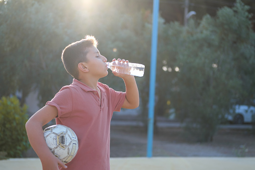 Young boy taking a break from soccer and drinking water.