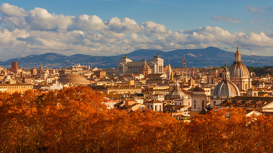 Autumn in Rome. View of the historical center skyline just before sunset with old monuments, baroque domes and red leaves