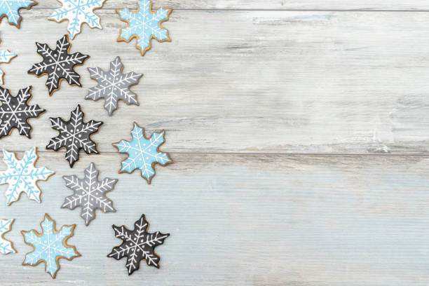 Chistmas background, white wood board arranged with homemade gingerbread cookies only snowflakes shapes. Top view, copy space. Festive mood, child party