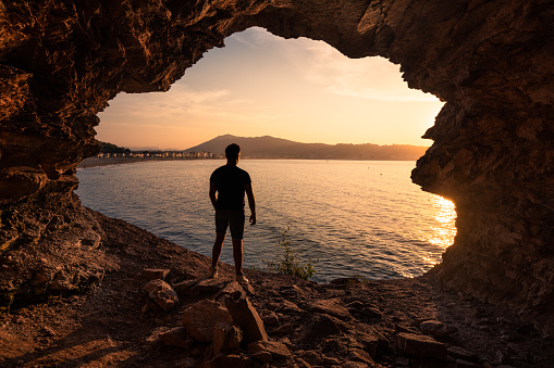 Young man silhouette in a coastal cave next to Hendaia beach, at the Basque Country.