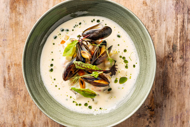 Seafood Soup with Mussels. Overhead view of  a bowl of seafood soup made with; mixed white fish, prawns and mussels. Flavoured with white wine and a strong fish stock and decorated with seasonal greens and balsamic vinegar. Chowder stock pictures, royalty-free photos & images