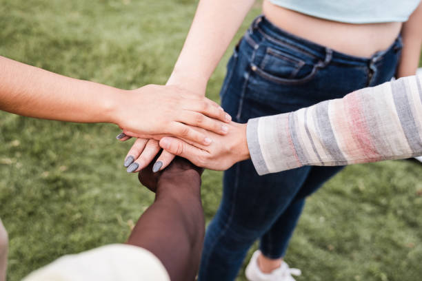 istock Young diverse group of people celebrating together stacking hands outdoor - Focus on hands 1344977965