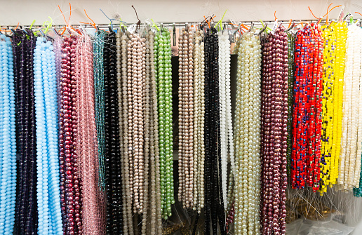 Multicolored beads made of gems strung on thread displayed on stand in store of jewelry accessories