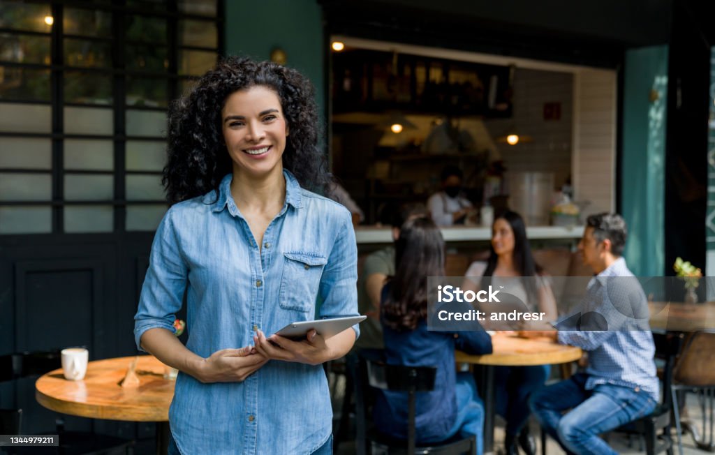 Portrait of a happy business owner of an outdoor restaurant smiling Portrait of a happy Latin American female business owner of an outdoor restaurant smiling while supervising the service and holding a tablet Entrepreneur Stock Photo
