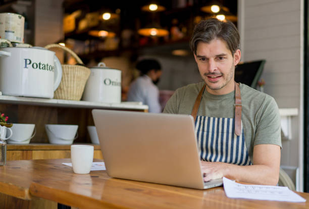 istock Happy manager working at a restaurant doing the accounting on a laptop 1344979749