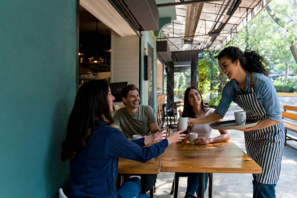 istock Happy waitress serving drinks to a group of customers at a cafe 1344979812