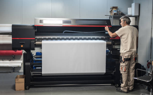 Technician operator works on large premium industrial printer plotter machine Technician worker operator works on large premium industrial printer and plotter machine in digital printshop office graphic print photos stock pictures, royalty-free photos & images