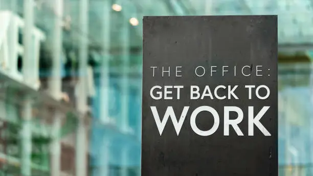The Office: Get back to Work on a city-center sign in front of a modern office building