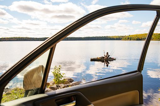 A  road trip to the lake. A fisherman out on a beautiful lake on his fishing kayak.