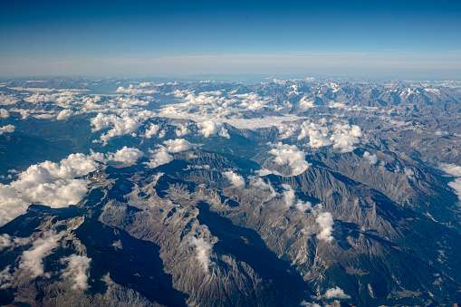 Aerial view of swiss alps. View of mountain and white cloud from the plane window. Tranquil scene.