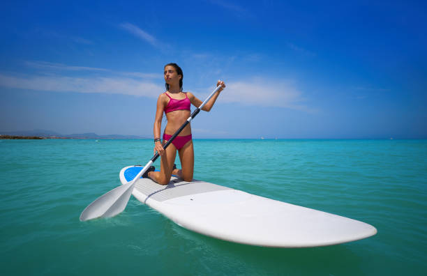 istock Girl rowing on knees on paddle surf SUP 1344988680