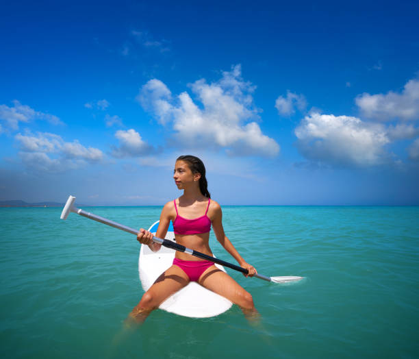 Girl relaxed sitting on paddle surf board SUP in summer