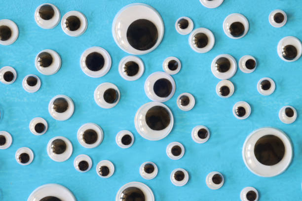 Stock photo showing elevated view of plastic toy, googly eyes on turquoise blue background.