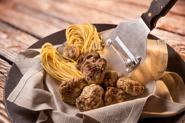 Alba white truffles Alba white truffles in napkin with raw egg tagliolini and steel truffle cutter on wooden background langhe photos stock pictures, royalty-free photos & images