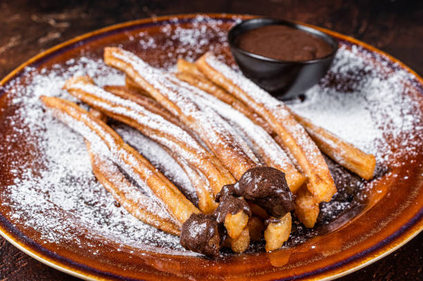istock Spanish tapas churros with sugar and chocolate sauce. Dark background. Top view 1344992482