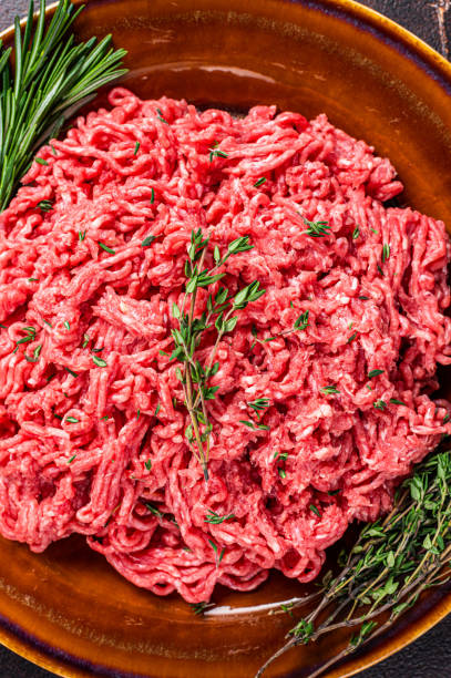 istock Raw mince beef and lamb meat on a rustic plate with herbs. Dark background. Top view 1344993556