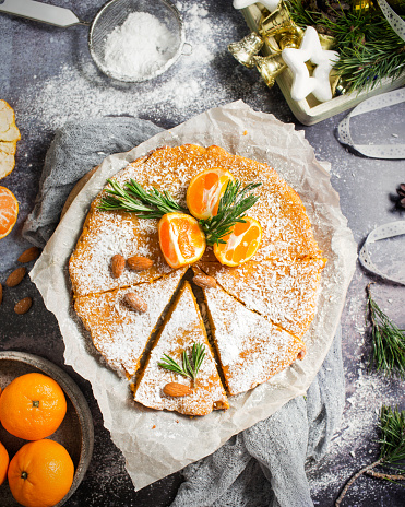 Christmas cake with tangerines. Tangerines and pastries on a gray background. New Year's atmosphere. Almond pastries for Christmas