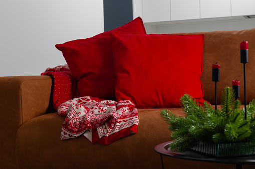 Room decorated for Christmas with candles, sofa, table, blanket and pillows. High quality photo