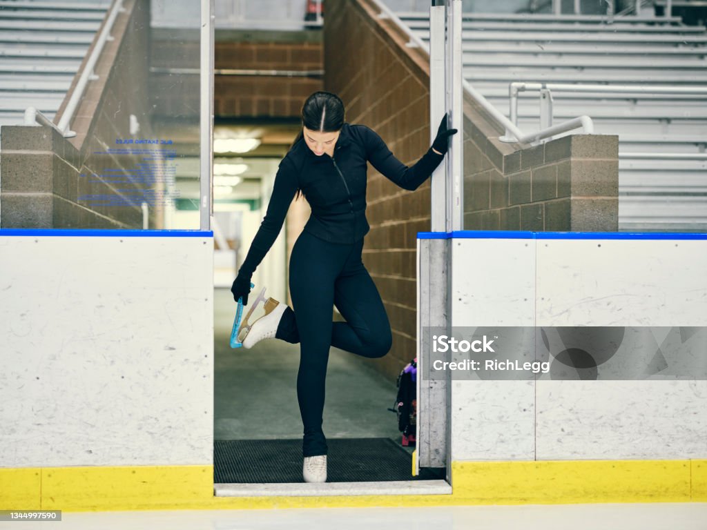 Figure Skater in Training A young woman competitive figure skater training in an empty ice rink arena. Figure Skating Stock Photo