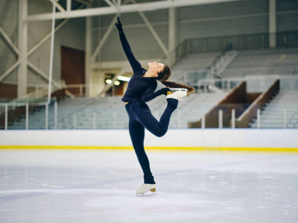 Figure Skater in Training A young woman competitive figure skater training in an empty ice rink arena. figure skating stock pictures, royalty-free photos & images