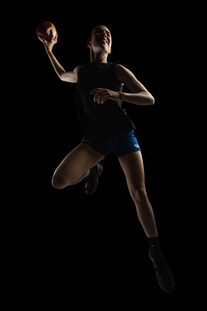 istock Handball player posing on dark background. Girl jumping with ball. 1344998440