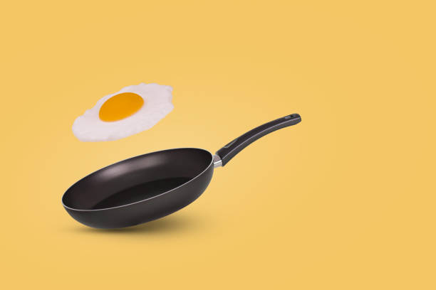 istock Minimal idea with a frying pan and a flying fried egg on a yellow background. Creative food concept. 1345001444