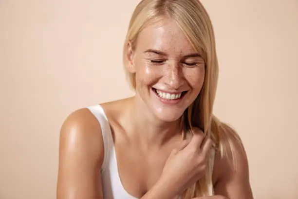Photo of Studio shot of a happy caucasian woman adjusting her hair with closed eyes