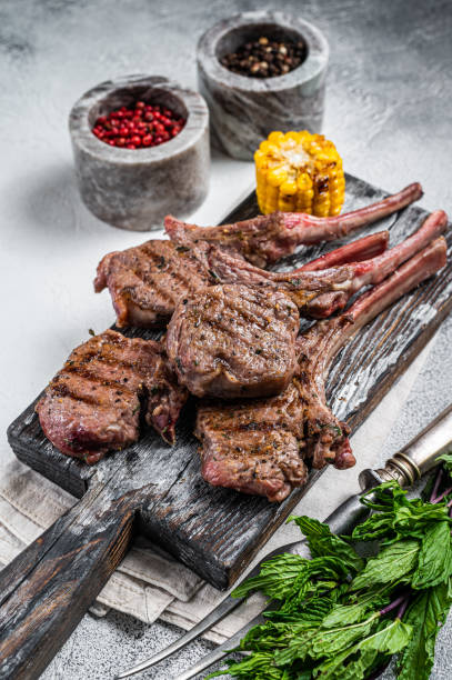 istock Roasted chops steaks of  lamb mutton on a wooden board. White background. Top view 1345005930