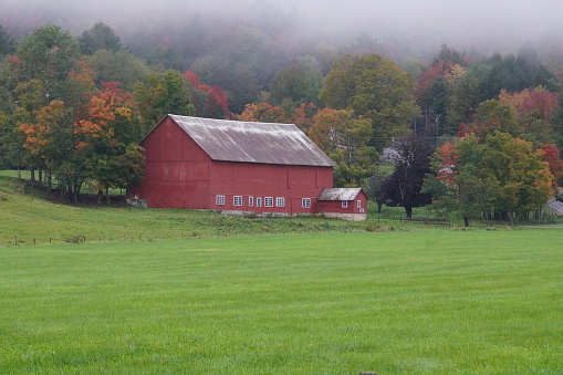 A red barn, surrounded by snow, is decorated for Christmas with a wreath