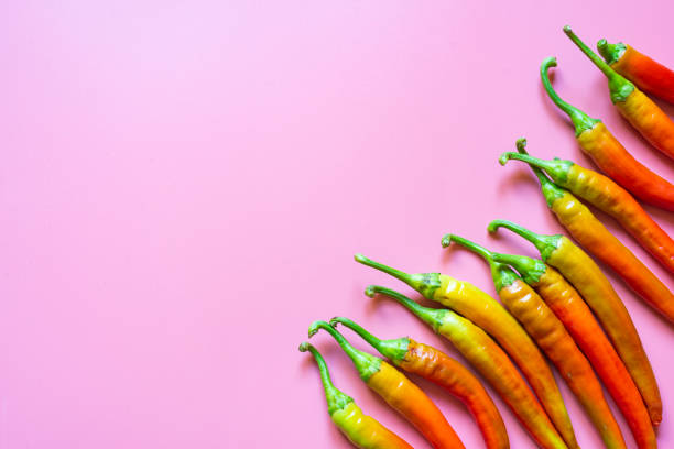 istock Fresh red and orange, hot peppers on pink background with copy space 1345008379