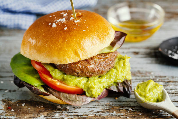 istock Burger with meat and avocado sauce served on wooden table. 1345009285