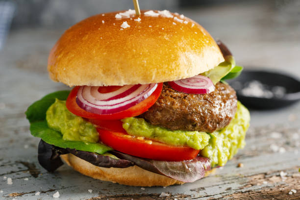 istock Burger with meat and avocado sauce served on wooden table. 1345009288