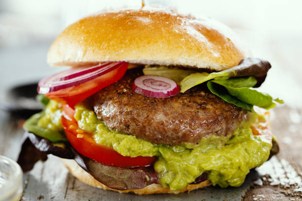 istock Burger with meat and avocado sauce served on wooden table. 1345009291