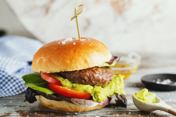 istock Burger with meat and avocado sauce served on wooden table. 1345009402