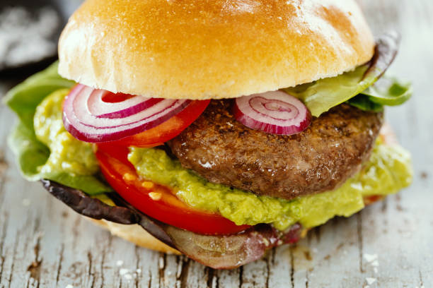 istock Burger with meat and avocado sauce served on wooden table. 1345009469