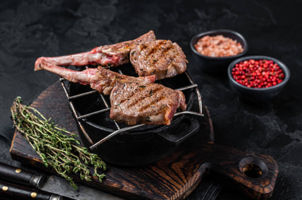istock Grilled lamb mutton meat chops steaks on a grill. Black background. Top view 1345010037