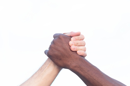 Close-up of a black African and a white Caucasian holding hands.