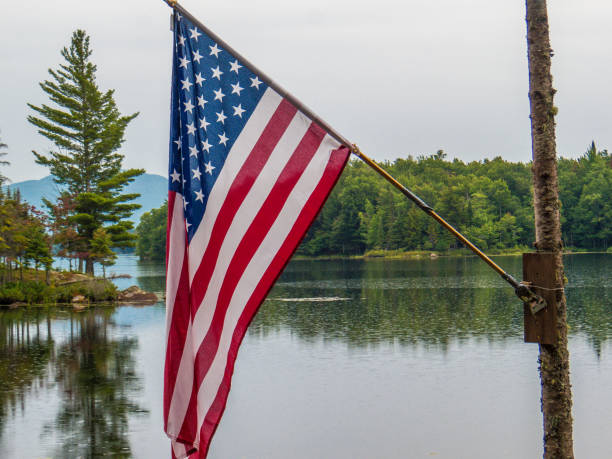 istock American flag waving next to a pond with mountains 1345011421