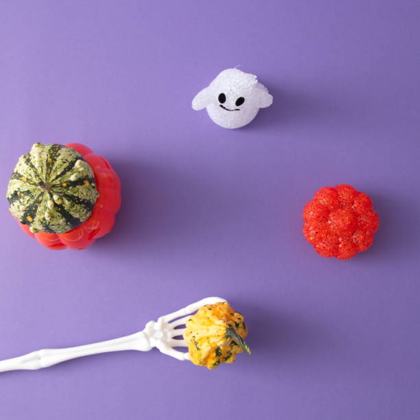 istock Pumpkins for Halloween and decoration with a ghost on a purple background with hand bones with copy space. Minimal scene flat lay. 1345011521