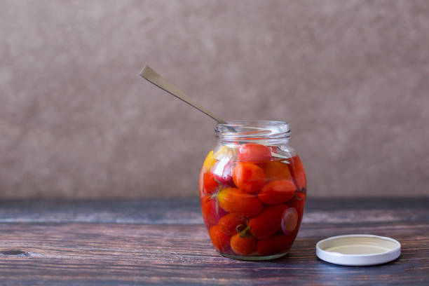 istock Pickled cherry tomatoes in glass jar on wooden background 1345012096