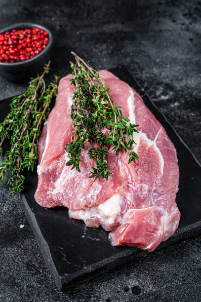 istock Raw pork shoulder meat cut on a marble board. Black background. Top view 1345012144