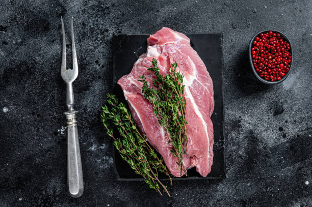 istock Raw pork shoulder meat cut on a marble board. Black background. Top view 1345012156